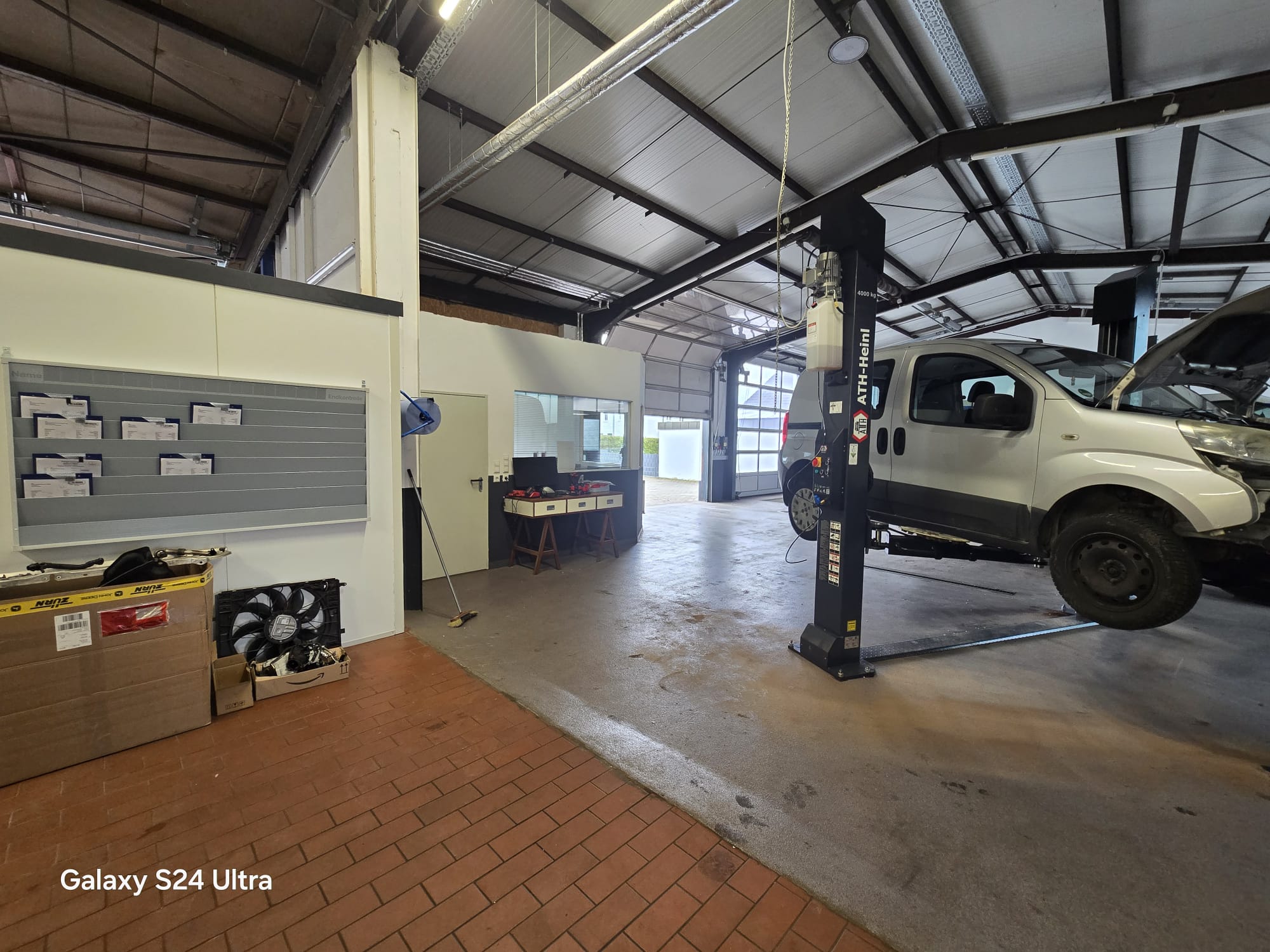 Werkstattimpression KFZ Wagner: Fahrzeug auf Hebebühne in moderner Halle